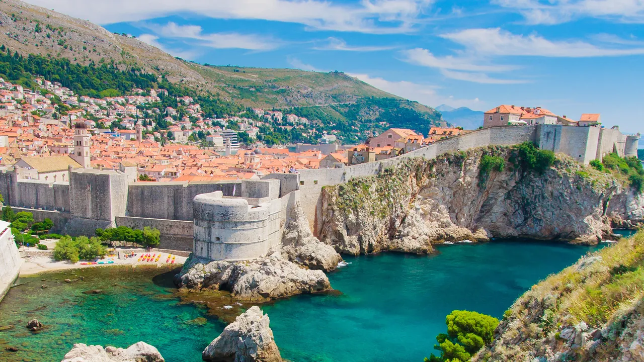 A traveler standing on a cliff overlooking the ocean at sunrise